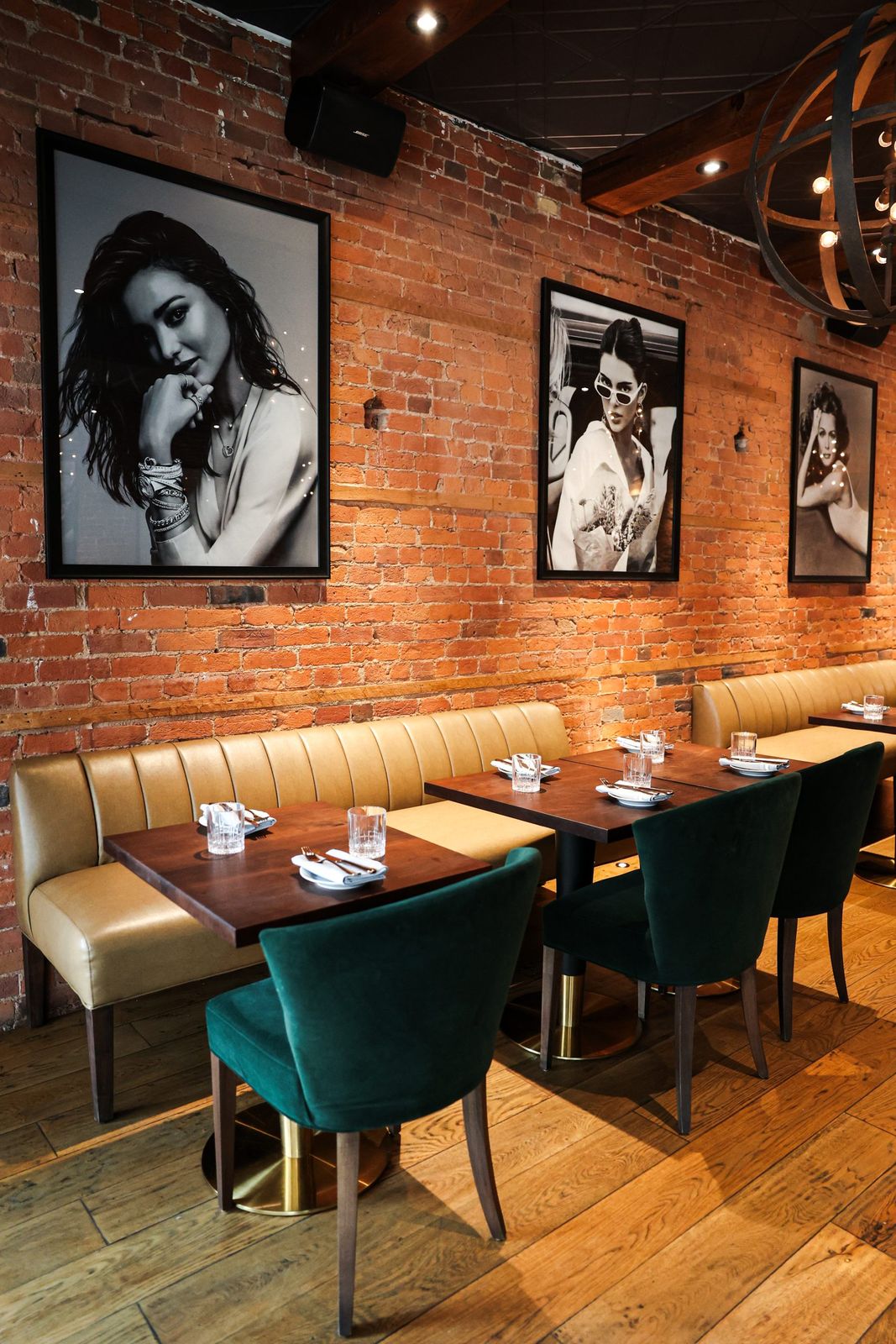 The Bistro Room on the main floor with brick walls and green velvet chairs